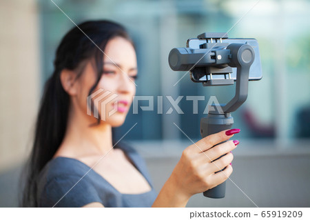 Blogger girl shoots a video about traveling on an electronic stabilizer. 65919209