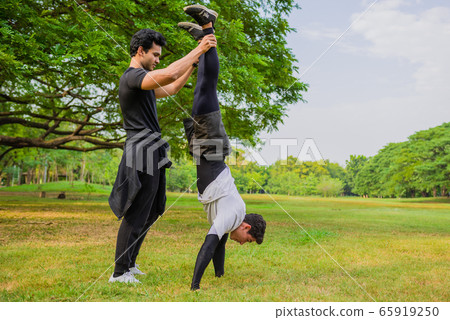 Sportsman trying a handstand on the grass against Sportsman trying a handstand on the grass against 65919250
