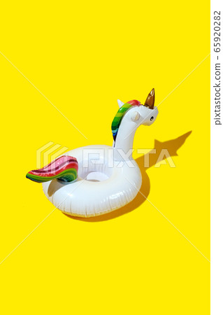 Inflatable unicorn pool toy on yellow background. 65920282