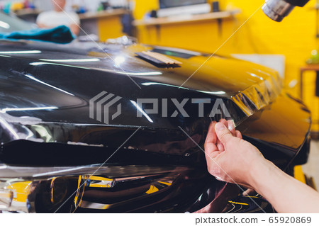 Transparent film, car paint protection, wrapping specialis. Car detailing. Selective focus. 65920869