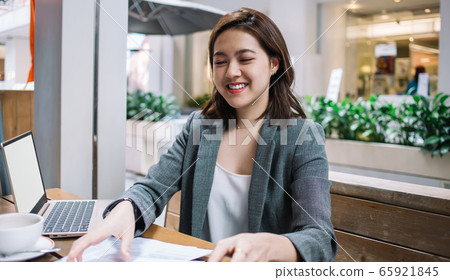Pleased remote worker organizing papers on table 65921845