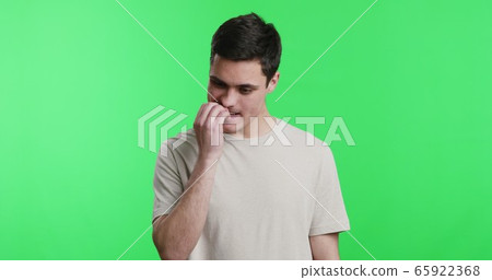 Nervous young man biting his nails uncontrollably Nervous young man biting his nails uncontrollably 65922368