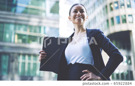 Young businesswoman in formal wear standing near office building Young businesswoman in formal wear standing near office building 65922884