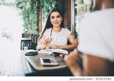 Smiling woman writing down ideas in notebook Smiling woman writing down ideas in notebook 65923398
