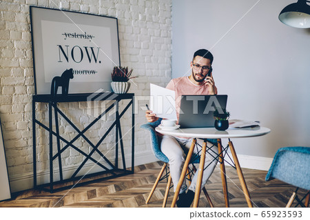 Serious male journalist processing information after interview with colleague Serious male journalist processing information after interview with colleague 65923593