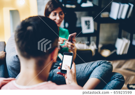 Back view of young husband chatting online via mobile phone 65923599