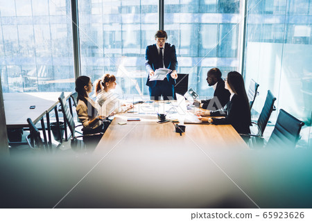 Displeased boss talking with employees during meeting 65923626