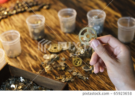Woman watchmaker works with gears. 65923658