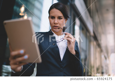 Executive lady having video call on tablet in business district Executive lady having video call on tablet in business district 65924175