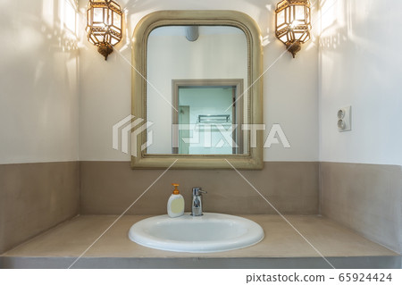 Bathroom with washbasin, mirror, lamps. European hotel design. Close-up. 65924424