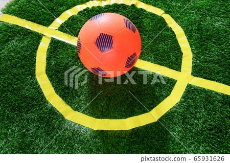 Orange soccer ball in center green field kids zone Orange soccer ball in center green field kids zone 65931626
