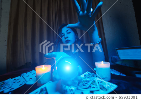 Woman fortune-teller guesses fate of night at table with candles Woman fortune-teller guesses fate of night at table with candles 65933091