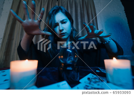 Woman fortune-teller guesses fate of night at table with candles Woman fortune-teller guesses fate of night at table with candles 65933093