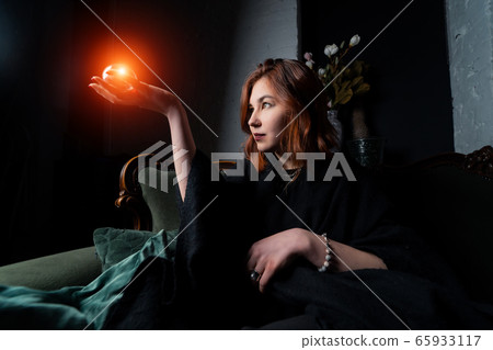 Woman in black suit holding crystal ball 65933117