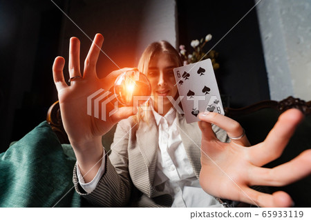 Woman in business suit holding crystal ball and six spade 65933119