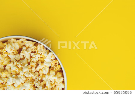 Popcorn closeup viewed from above on yellow background. Flat lay of pop corn bowl. Top view 65935096
