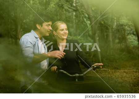Young couple going for a bike ride in the green 65935536