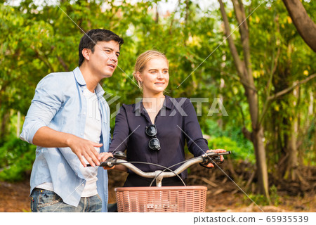 Young couple in love on bikes in the park Young couple in love on bikes in the park 65935539