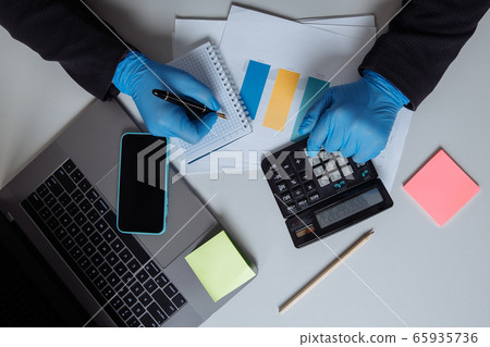 Businessman working on office desk. Working with laptop and calculator making a note something of idea. Top view Businessman working on office desk. Working with laptop and calculator making a note something of idea. Top view 65935736