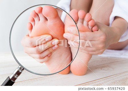 用放大鏡放大觸摸鞋底的女人。 用放大鏡放大觸摸鞋底的女人。 65937420