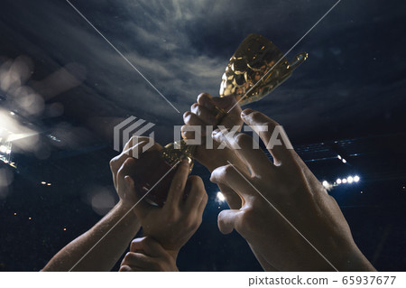Award of victory, male hands tightening the cup of winners against cloudy dark sky 65937677