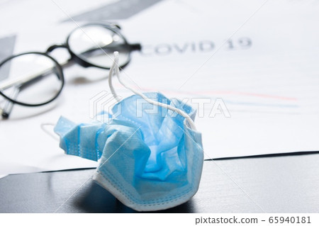 End of pandemic coronavirus and isolation. Used crumpled medical mask against glasses and chart for reducing the incidence of morbidity and mortality. End of pandemic coronavirus and isolation. Used crumpled medical mask against glasses and chart for reducing the incidence of morbidity and mortality. 65940181