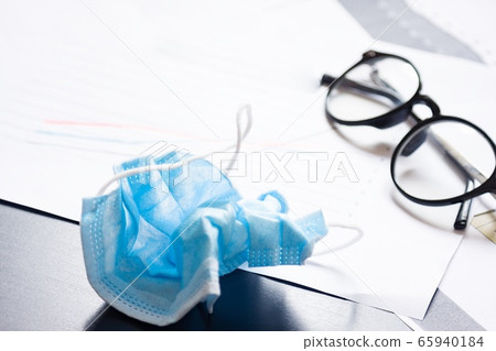 End of pandemic coronavirus and isolation. Used crumpled medical mask against glasses and chart for reducing the incidence of morbidity and mortality. 65940184