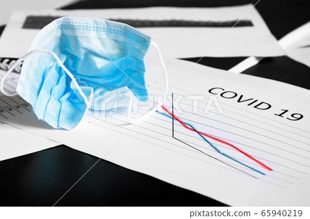 End of pandemic coronavirus and isolation. Used crumpled medical mask on chart for reducing the incidence of morbidity and mortality. End of pandemic coronavirus and isolation. Used crumpled medical mask on chart for reducing the incidence of morbidity and mortality. 65940219