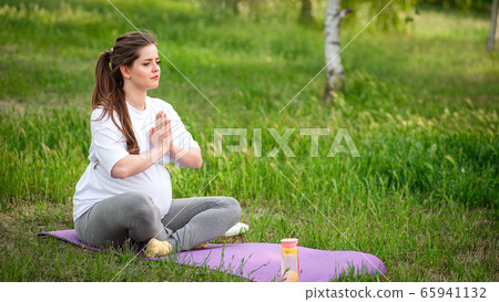 Healthy pregnant woman doing yoga in nature 65941132