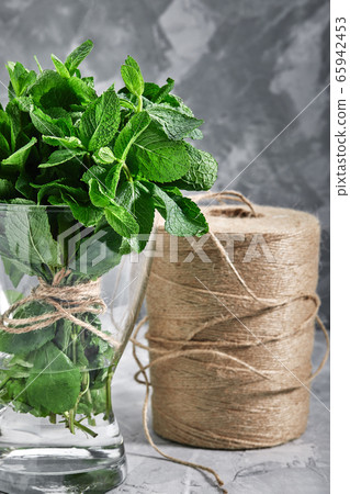 A bunch of fresh mint in a glass vase and water. Minimalism of decor, natural product, copy space A bunch of fresh mint in a glass vase and water. Minimalism of decor, natural product, copy space 65942453