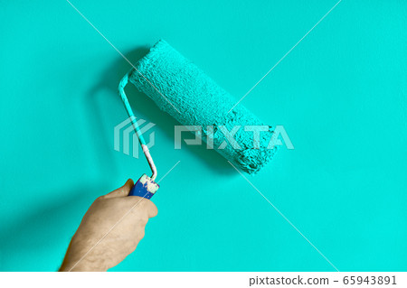 Male hand painting wall with paint roller. Painting apartment, renovating with turquoise color paint Male hand painting wall with paint roller. Painting apartment, renovating with turquoise color paint 65943891