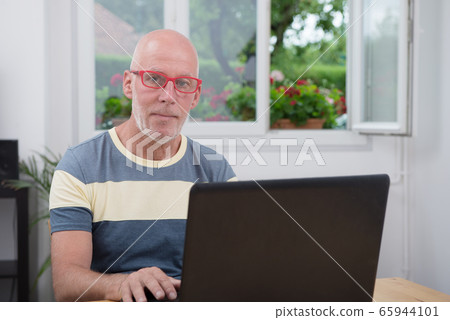 mature man with laptop in his home 65944101