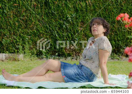 mature woman is resting in the garden 65944103