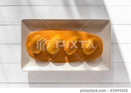 Fried meat croquettes with vegetable cream sauce on white plate at sunny kitchen. Top view at white wooden background. Fried meat croquettes with vegetable cream sauce on white plate at sunny kitchen. Top view at white wooden background. 65944302