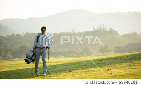 Golfer asian man walking in fairway with bag golf with club in sunlight. Golfer asian man walking in fairway with bag golf with club in sunlight. 65946191