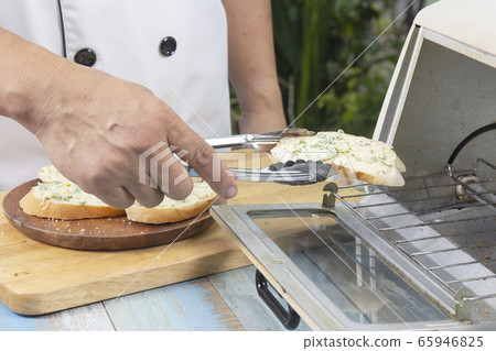 Chef put garlic bread to the oven by tongs Chef put garlic bread to the oven by tongs 65946825