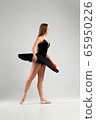 Girl in a black ballet dress. Ballerina in a dark ballet tutu on a light background. The young ballerina is warming up 65950226