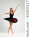 Girl in a black ballet dress. Ballerina in a dark ballet tutu on a light background. The young ballerina is warming up 65950227