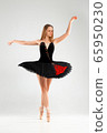 Girl in a black ballet dress. Ballerina in a dark ballet tutu on a light background. The young ballerina is warming up 65950230