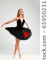 Girl in a black ballet dress. Ballerina in a dark ballet tutu on a light background. The young ballerina is warming up 65950231