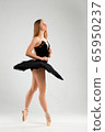 Girl in a black ballet dress. Ballerina in a dark ballet tutu on a light background. The young ballerina is warming up 65950237