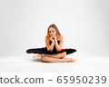 Girl in a black ballet dress. Ballerina in a dark ballet tutu on a light background. The young ballerina is warming up 65950239