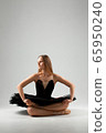 Girl in a black ballet dress. Ballerina in a dark ballet tutu on a light background. The young ballerina is warming up 65950240