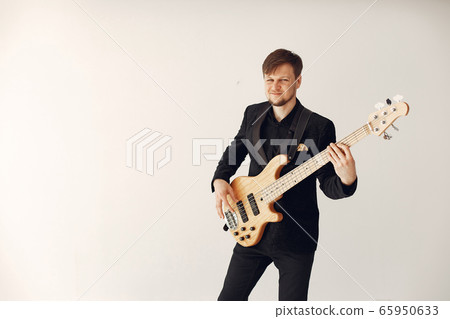 Man in black suit standing with a guitar 65950633