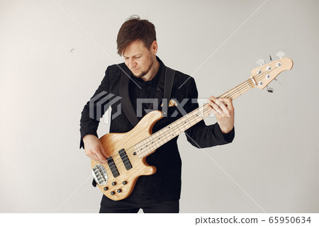 Man in black suit standing with a guitar 65950634