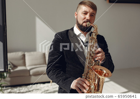 Man in black suit standing with a saxophone Man in black suit standing with a saxophone 65950641