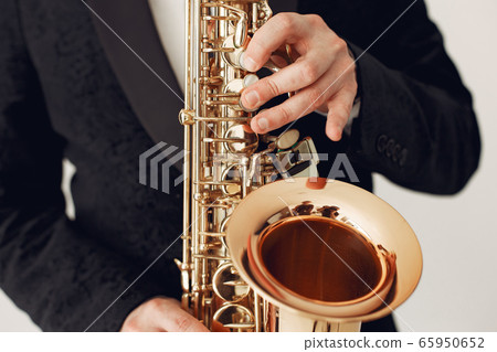 Man in black suit standing with a saxophone Man in black suit standing with a saxophone 65950652