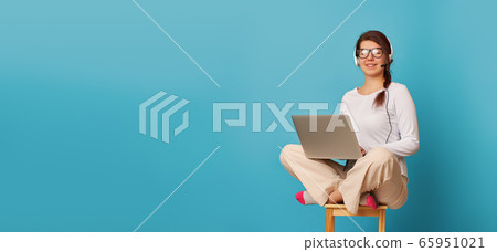 Woman is siting in lotus position on a chair with a laptop. Woman is siting in lotus position on a chair with a laptop. 65951021