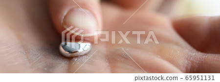 Male hand holding piece of liquid gallium 65951131