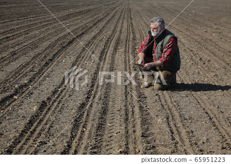 Farmer in field after sowing analyze land 65951223
